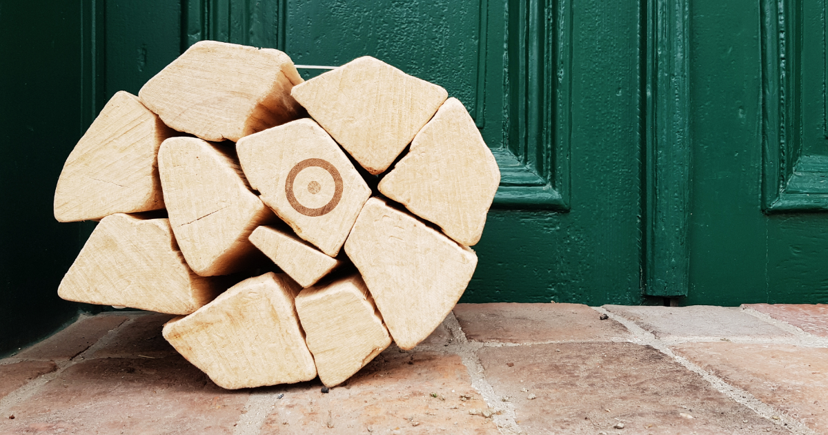 Stapel geformter Holzblöcke mit einem runden Zielkreis auf dem mittleren Block vor einer grünen Tür und Steinboden.
