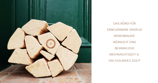 Holzblöcke stapeln sich vor einer grünen Tür; rechts Textfeld mit Weihnachts- und Neujahrsgruß vom Büro für erneuerbare Energie.