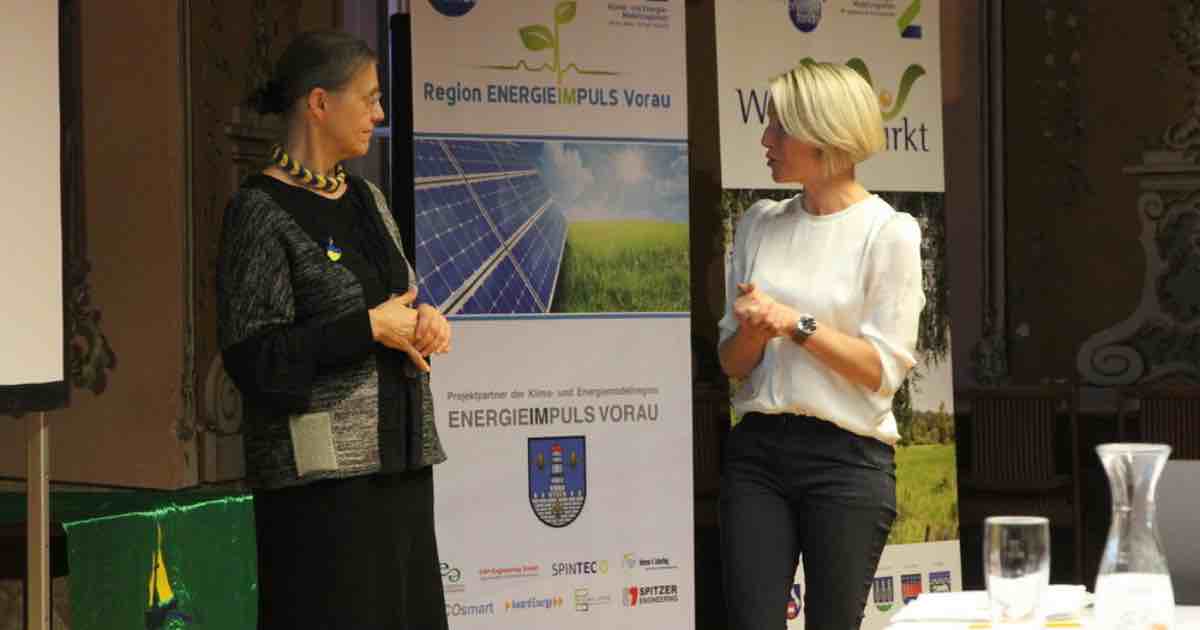 Zwei Personen im Gespräch auf einer Bühne, neben Bannern für Energieimpuls Vorau.
