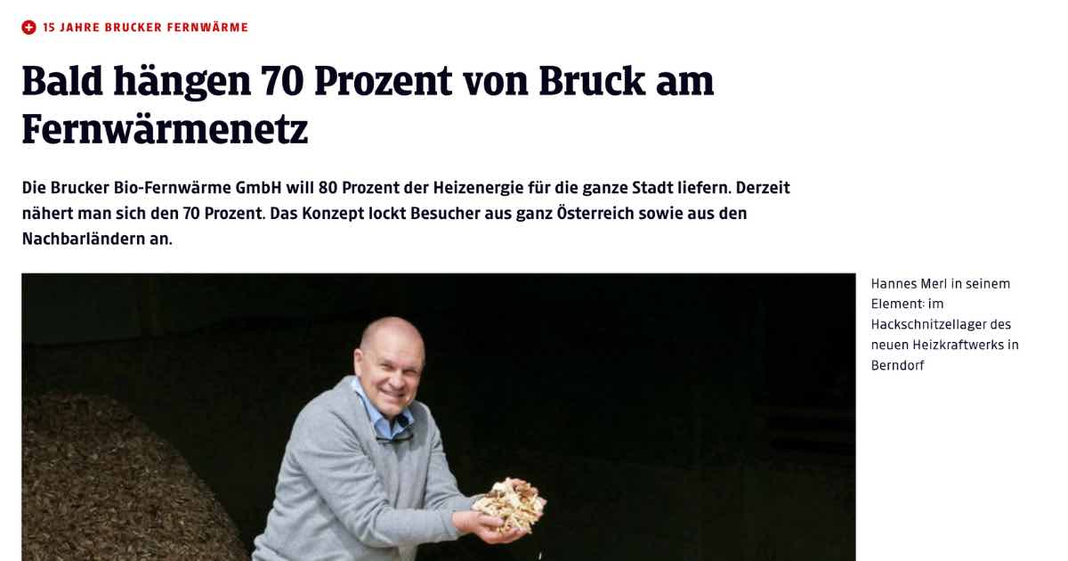 Neutral dargestellte Person hält Holzspäne in einem HackSchnitzellager eines Heizkraftwerks, dunkler Hintergrund.