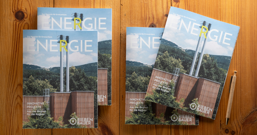 Vier Ausgaben des Magazins ENERGIE liegen auf einem Holztisch; Kraftwerksbau im Vordergrund, daneben ein Stift.