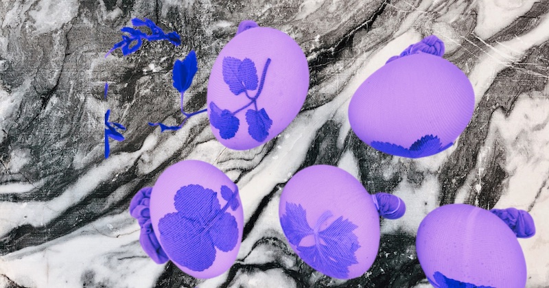 Mehrere violette Ostereier mit Blattmuster auf einer marmorierten Oberfläche.