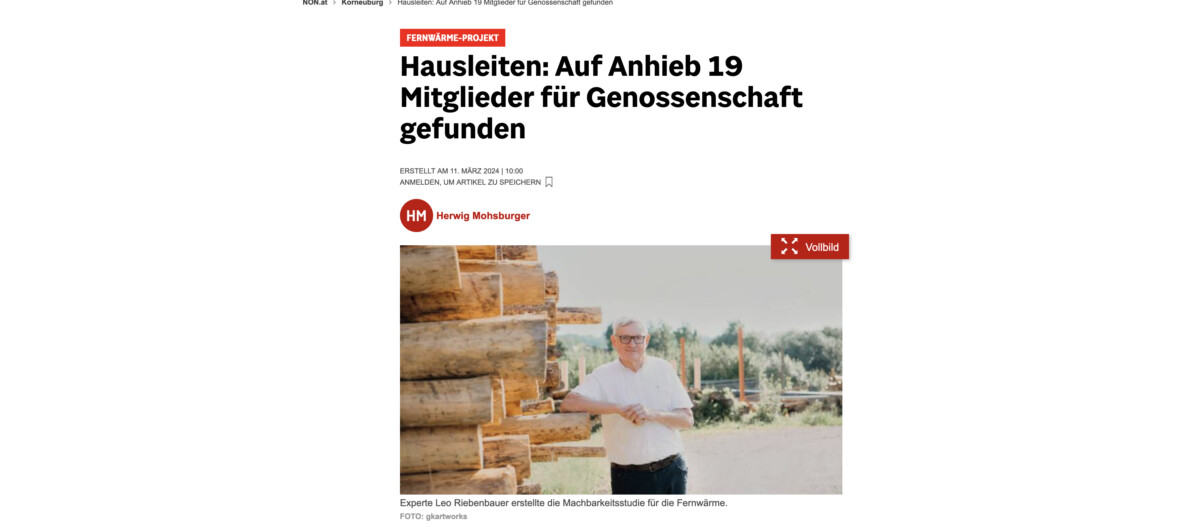 Person steht neben einem Holzstapel im Freien, Arme locker verschränkt, weißes Hemd und Brille; Hintergrund mit Bäumen.