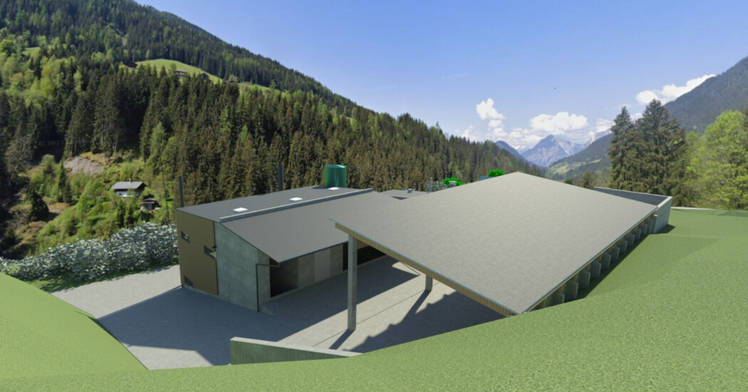Moderne Baustruktur mit großem Vordach, in bergiger Waldlandschaft mit grünen Hügeln und schneebedeckten Bergen im Hintergrund.