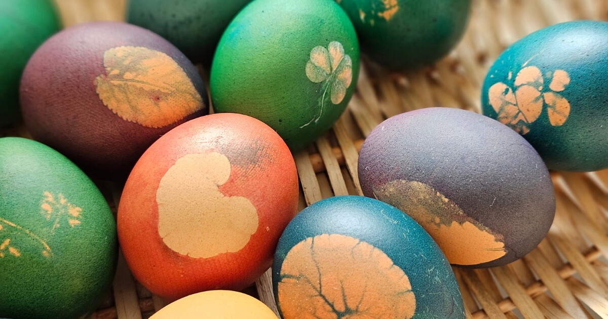 Bunte Ostereier mit Blatt- und Kleeblatt-Motiven in einem Korb aus Geflecht.