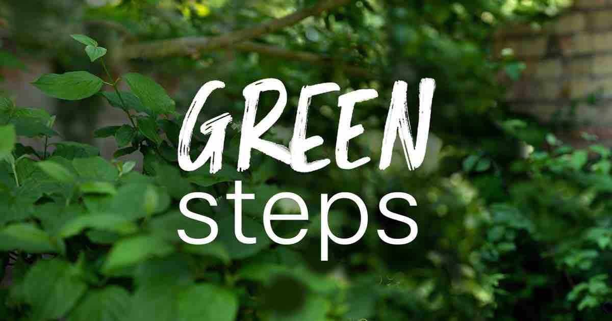 Weiße Schriftzug-Grafik GREEN steps über grünem Laub; unscharfer Gartenhintergrund.