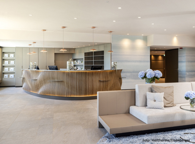 Moderne Hotellobby mit gewellter Holz-Rezeption, heller Sitzecke und blau-weißen Hydrangea-Blüten.
