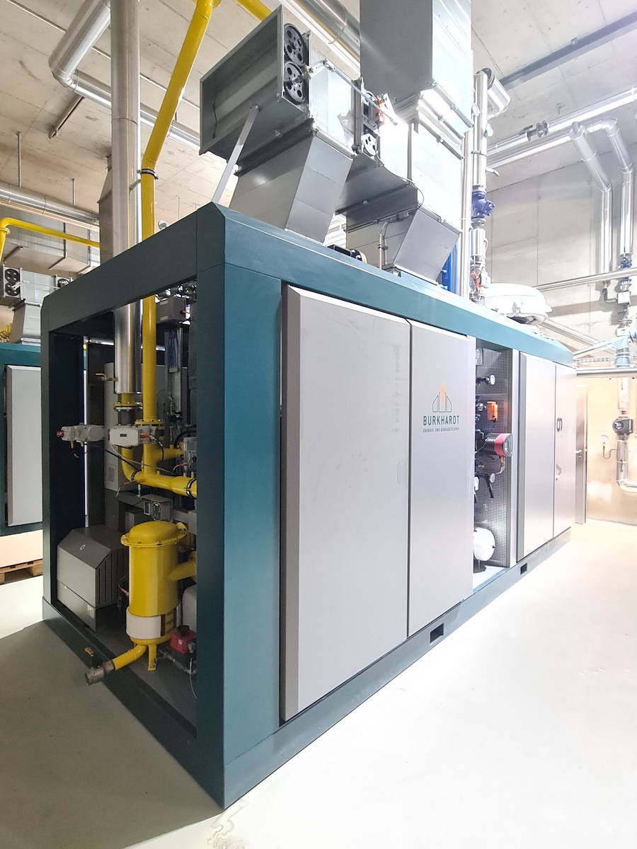 Große industrielle Anlage mit blauem Rahmen, grauen Paneelen, gelben Rohrleitungen und Pumpen; Burkhardt-Logo sichtbar.