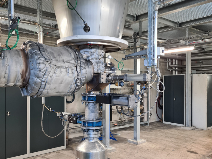 Industrielle Anlage mit isolierten Rohrleitungen, Ventilen und Metallkomponenten in einem Technikraum.