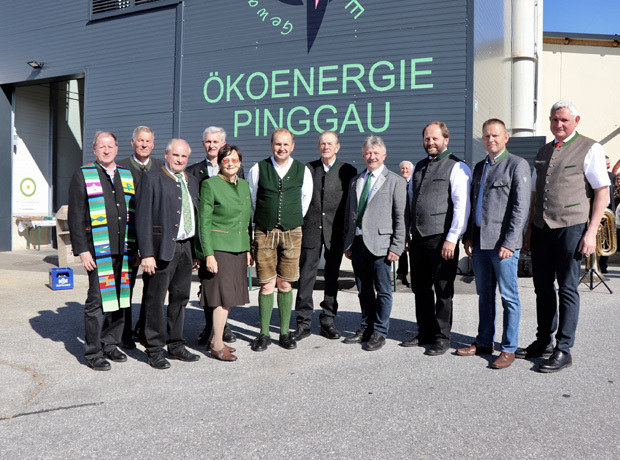 Gruppe von Personen in traditioneller und formeller Kleidung vor einem Gebäude mit der Aufschrift ÖKOENERGIE PINGGAU.